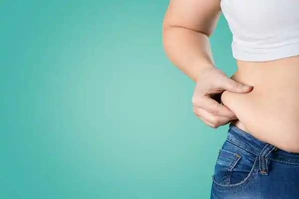 Image of woman pinching her love handles to show weight gain Warwickshire