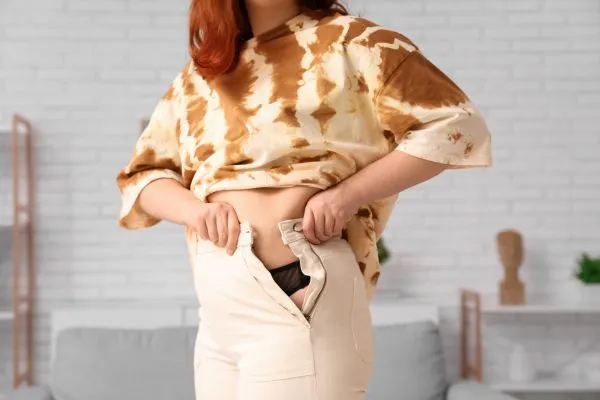 Image of woman trying to do her trousers up after pregnancy weight gain Warwickshire